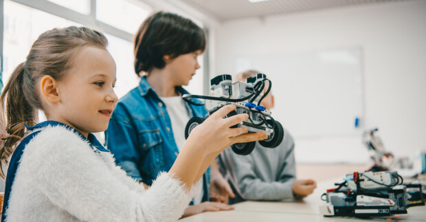 Girl holding robot in robotics class